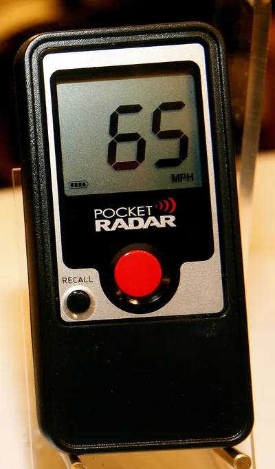 The original Pocket Radar Classic with a red button, showing 65 mph